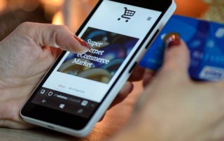 Frauenhände mit Handy und Kreditkarte beim Online-Shopping